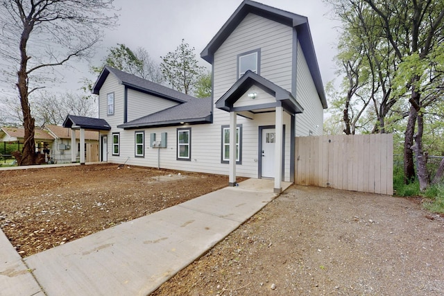 shotgun-style home with fence and roof with shingles