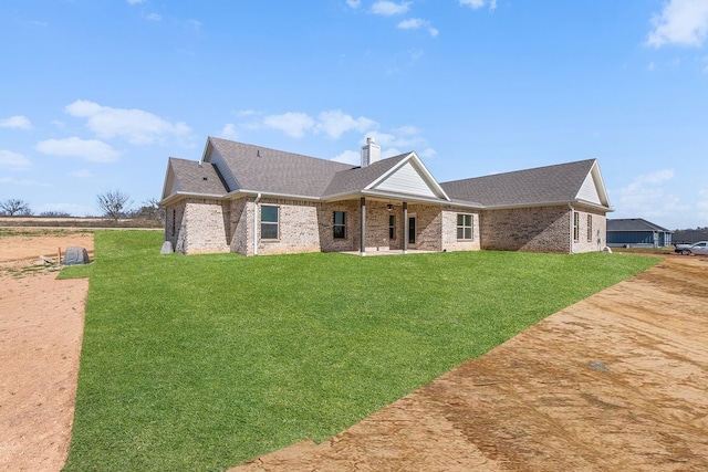 405 Red Roan Rdg, Brock, TX 76087 - rear view of house featuring a yard, a chimney, brick siding, and a shingled roof