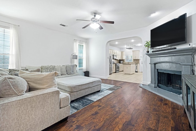 2725 Albatross Ln, Fort Worth, TX 76177 - living area featuring a ceiling fan, a fireplace with raised hearth, arched walkways, and light wood-style flooring