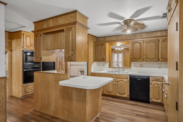 kitchen with a center island, ceiling fan, wood finished floors, black appliances, and a sink