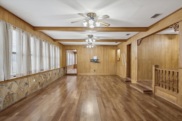 spare room with wood finished floors, beamed ceiling, a ceiling fan, and visible vents