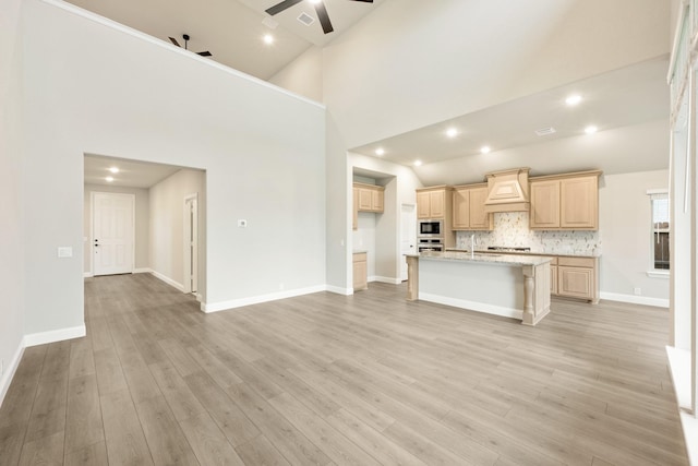 4400 Copper Point Dr, Fort Worth, TX 76036 - kitchen featuring a ceiling fan, light brown cabinets, black microwave, an island with sink, and decorative backsplash