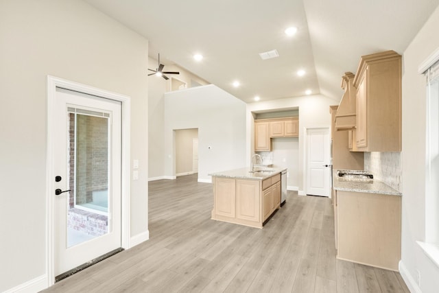 4400 Copper Point Dr, Fort Worth, TX 76036 - kitchen featuring light brown cabinetry, appliances with stainless steel finishes, vaulted ceiling, a center island with sink, and light wood finished floors