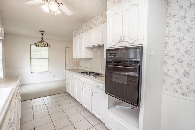 kitchen featuring oven, wainscoting, light carpet, a textured ceiling, and stainless steel electric stovetop