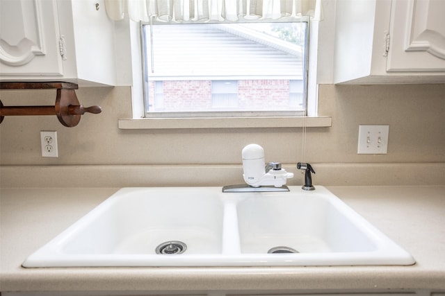 interior details with a sink, white cabinets, and light countertops