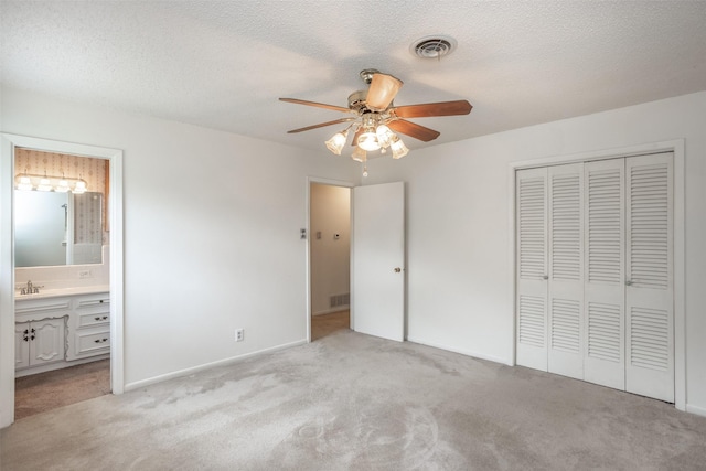 unfurnished bedroom with connected bathroom, visible vents, light carpet, and a closet