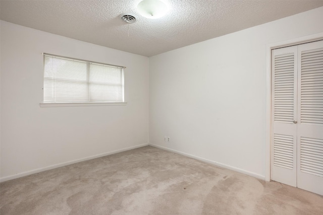 unfurnished bedroom featuring a closet, baseboards, visible vents, and light carpet
