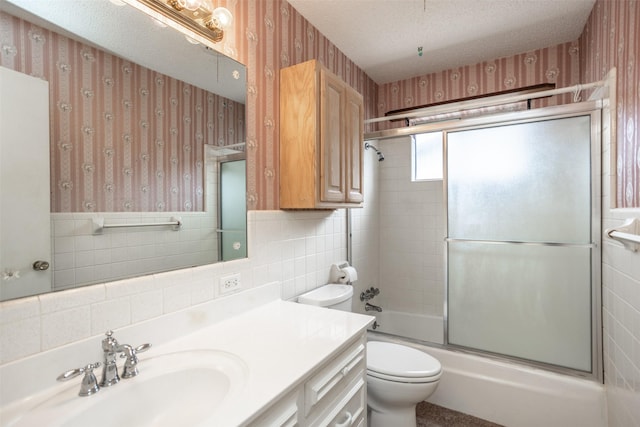 bathroom with vanity, toilet, wallpapered walls, tile walls, and bath / shower combo with glass door