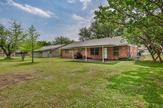 rear view of house featuring fence, a patio, a yard, and brick siding