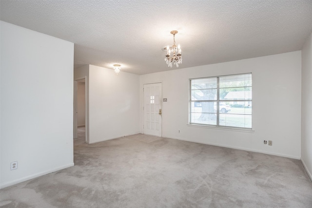 interior space with baseboards, a textured ceiling, carpet, and a chandelier
