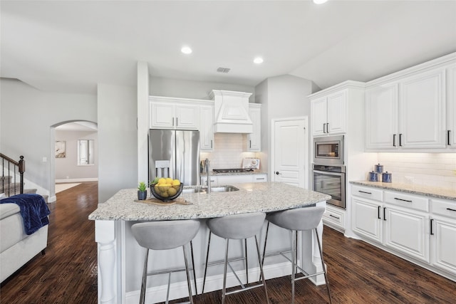9413 Lakeway Dr, Denton, TX 76226 - kitchen featuring appliances with stainless steel finishes, arched walkways, a kitchen bar, backsplash, and lofted ceiling