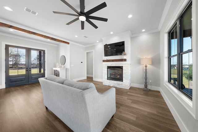 living room featuring dark wood-style flooring, a fireplace, visible vents, and a wealth of natural light