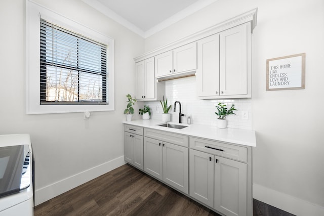kitchen featuring dark wood-style floors, baseboards, a sink, light countertops, and tasteful backsplash