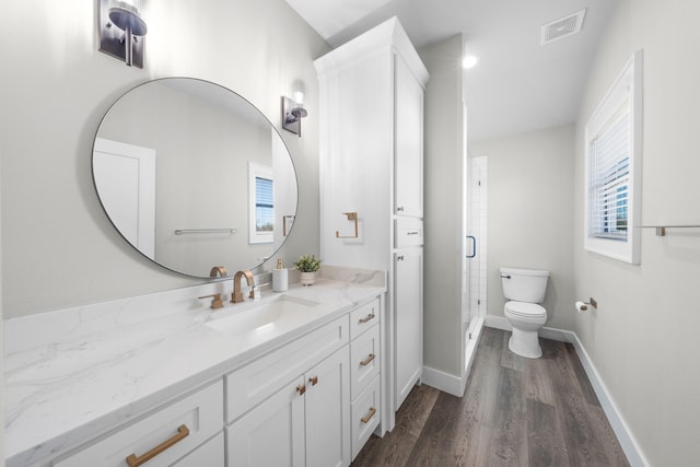 bathroom with visible vents, toilet, wood finished floors, a shower stall, and vanity