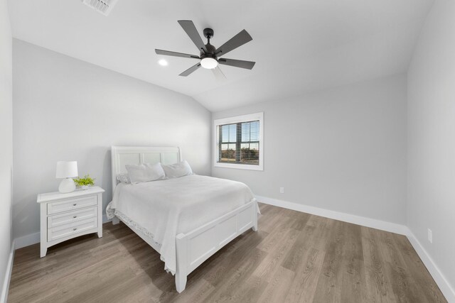 bedroom with visible vents, baseboards, wood finished floors, and vaulted ceiling