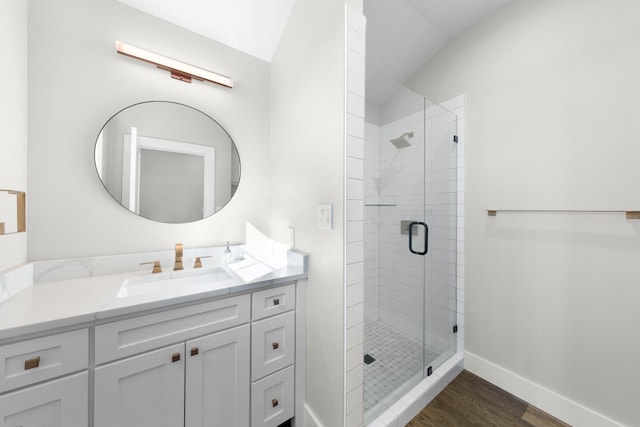 bathroom with a shower stall, vanity, baseboards, and wood finished floors