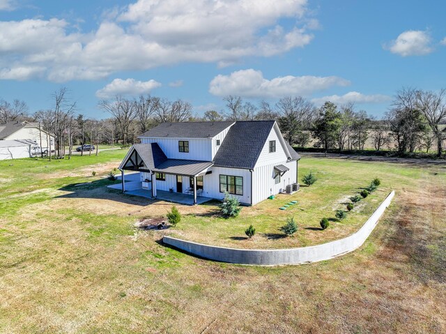 back of house featuring a shingled roof, a lawn, and metal roof