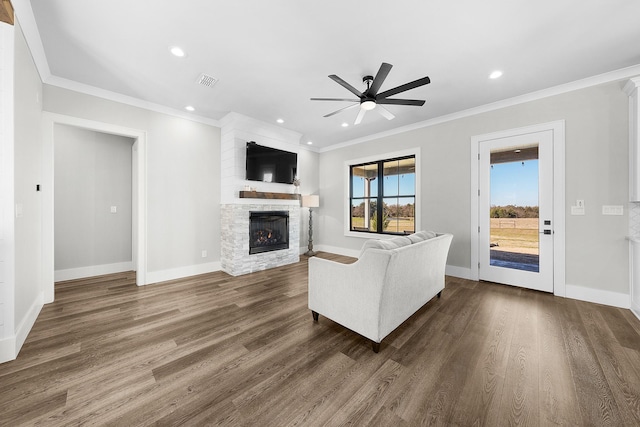 unfurnished living room featuring a ceiling fan, visible vents, a stone fireplace, dark wood-type flooring, and crown molding