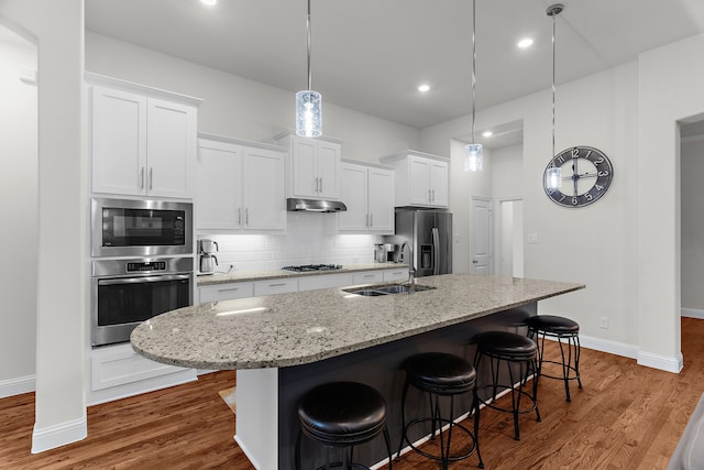 3509 Concord Dr, Melissa, TX 75454 - kitchen with stainless steel appliances, a sink, under cabinet range hood, a center island with sink, and wood finished floors