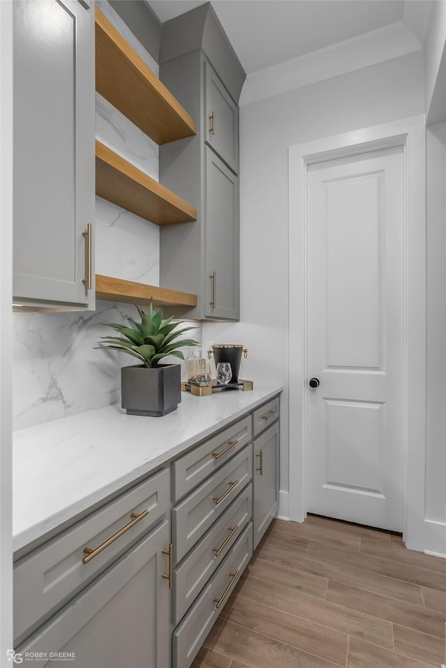 kitchen featuring decorative backsplash, open shelves, gray cabinetry, and wood finish floors
