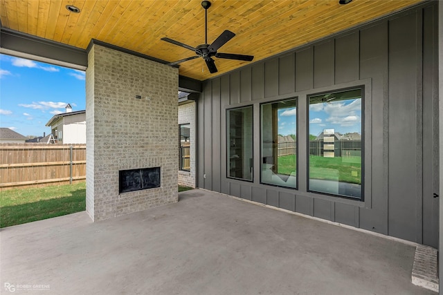 view of patio / terrace featuring fence, a ceiling fan, and an outdoor brick fireplace