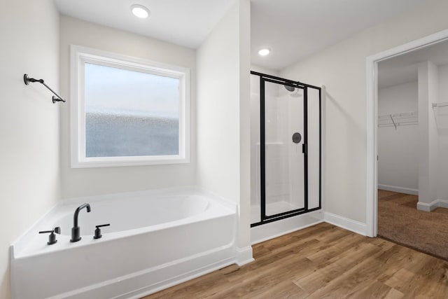 214 Briarwood Dr, Nevada, TX 75173 - bathroom featuring wood finished floors, baseboards, a stall shower, a spacious closet, and a bath