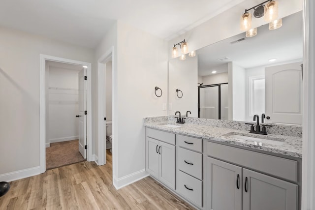214 Briarwood Dr, Nevada, TX 75173 - bathroom featuring double vanity, visible vents, wood finished floors, and a sink