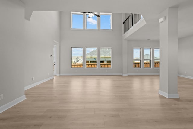 2012 Tolleson Dr, Fort Worth, TX 76008 - unfurnished living room featuring light wood finished floors, a chandelier, and a towering ceiling