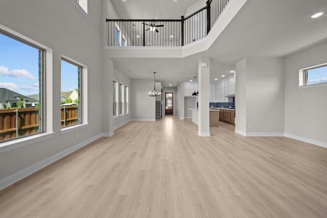 2012 Tolleson Dr, Fort Worth, TX 76008 - unfurnished living room featuring a chandelier, light wood-style flooring, recessed lighting, and a towering ceiling