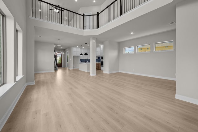 2012 Tolleson Dr, Fort Worth, TX 76008 - unfurnished living room with a high ceiling, a chandelier, and light wood finished floors