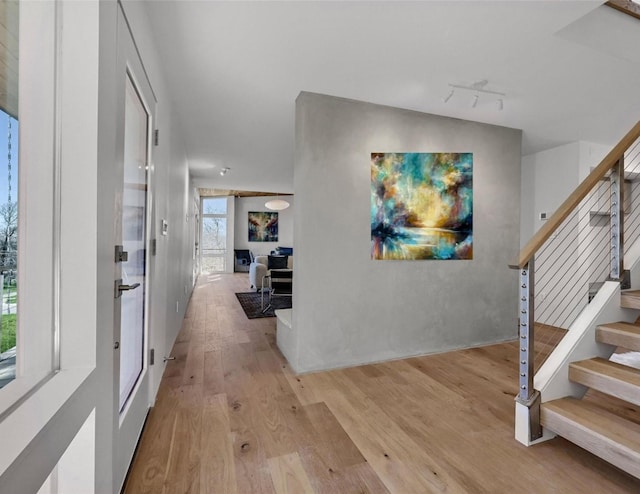 entrance foyer with stairway, rail lighting, and light wood-style floors