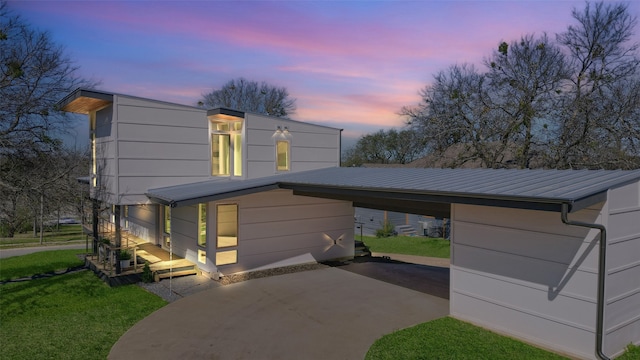 contemporary home featuring a front lawn, driveway, and metal roof