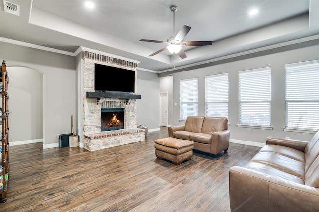 6565 Oak Point Cir, Royse City, TX 75189 - living area featuring a tray ceiling, wood finished floors, arched walkways, a ceiling fan, and a stone fireplace