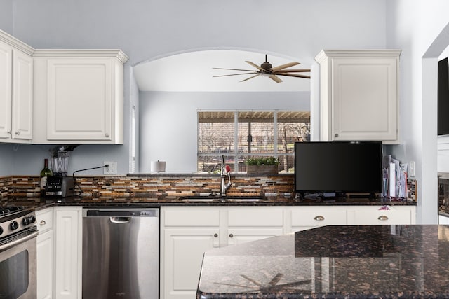 kitchen featuring a ceiling fan, a sink, dark stone countertops, white cabinetry, and stainless steel appliances