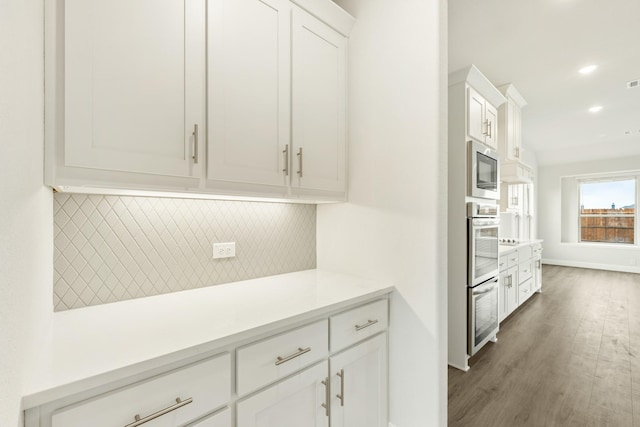 817 Lakewood Ct, Midlothian, TX 76065 - kitchen with backsplash, light countertops, white cabinetry, stainless steel appliances, and wood finished floors