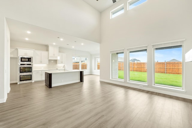 817 Lakewood Ct, Midlothian, TX 76065 - unfurnished living room with a sink, light wood finished floors, ceiling fan, baseboards, and high vaulted ceiling