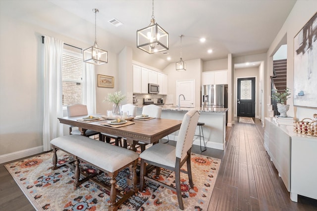 dining room with baseboards, vaulted ceiling, dark wood finished floors, and a chandelier