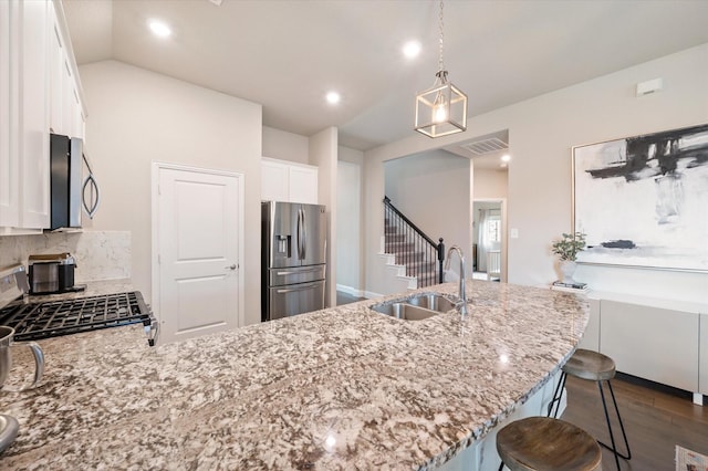 kitchen featuring appliances with stainless steel finishes, light stone countertops, a sink, a peninsula, and dark wood-style floors