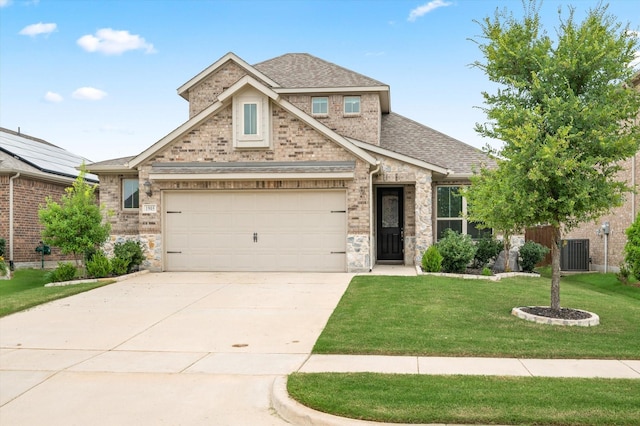 traditional home featuring a garage, a front lawn, roof with shingles, central AC unit, and concrete driveway
