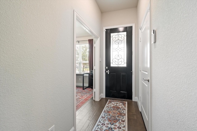 entryway featuring a textured wall, dark wood-style floors, and baseboards