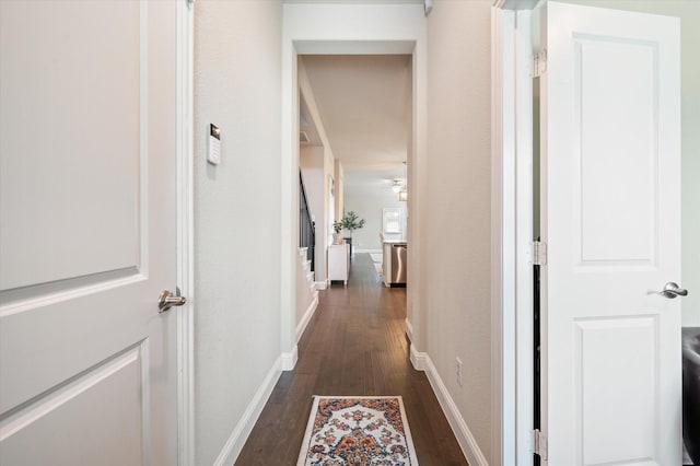 hallway featuring baseboards and dark wood-type flooring