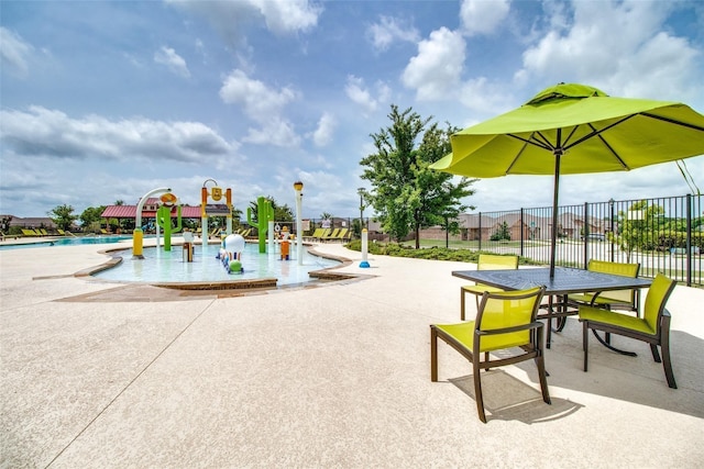 view of playground with fence, a patio area, a water play area, and a community pool