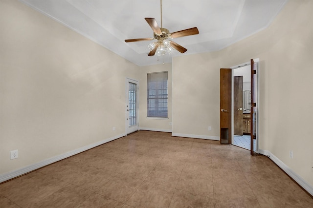 unfurnished room featuring a raised ceiling, a ceiling fan, and baseboards