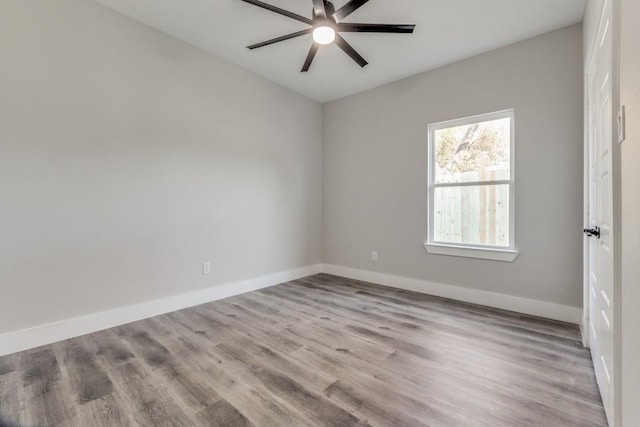 spare room featuring wood finished floors, baseboards, and ceiling fan