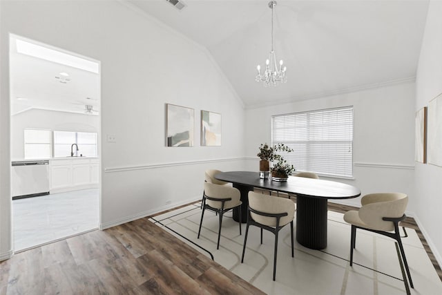 dining area with vaulted ceiling, a chandelier, wood finished floors, baseboards, and ornamental molding