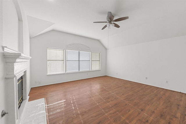 unfurnished living room with ceiling fan, vaulted ceiling, wood finished floors, and a glass covered fireplace