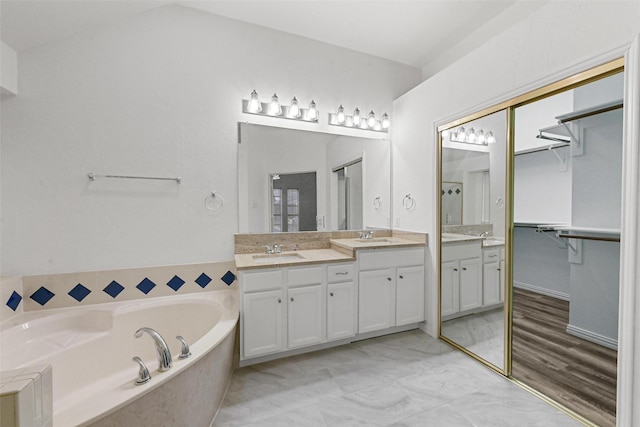 bathroom with vanity, a garden tub, and a spacious closet