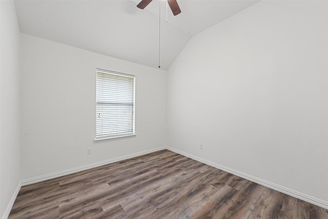 spare room with lofted ceiling, dark wood finished floors, a ceiling fan, and baseboards