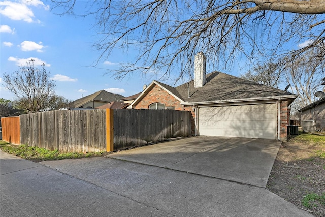garage with concrete driveway, fence, and central air condition unit