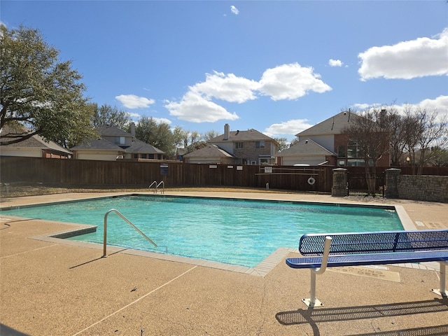 community pool featuring fence, a patio area, and a residential view